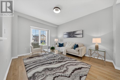 A well-lit living room with a rug, a couch, a chair, and a painting on the wall.
