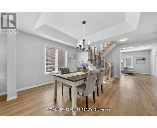 A dining room with a table and chairs and a staircase in the background.