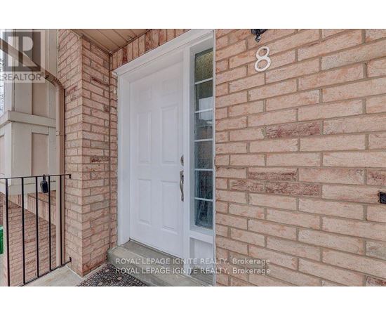 A white door is on the brick wall of a house.