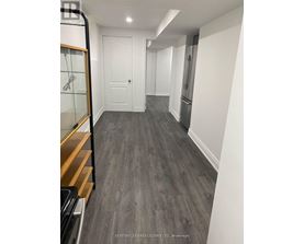 A hallway with a white door and a fridge on the right side.