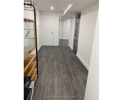 A hallway with a white door and a fridge on the right side.