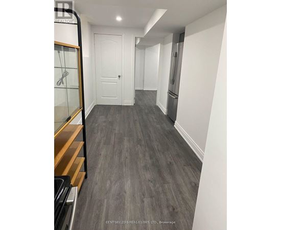 A hallway with a white door and a fridge on the right side.