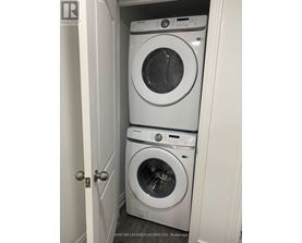 Two white front load washing machines in a small closet.