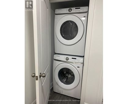 Two white front load washing machines in a small closet.