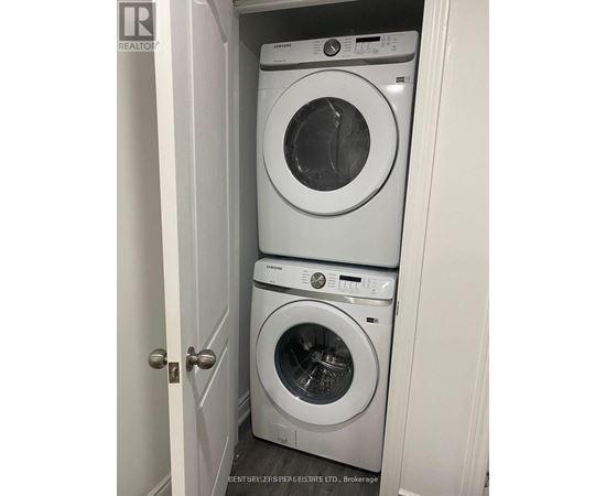 Two white front load washing machines in a small closet.