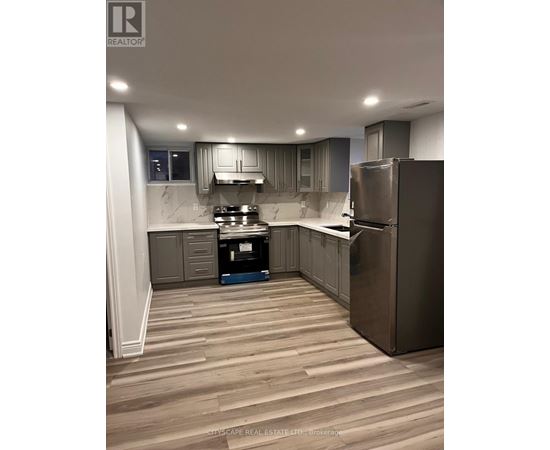 A kitchen with wooden flooring and stainless steel appliances.