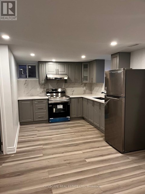 A kitchen with wooden flooring and stainless steel appliances.