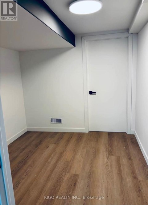A room with a white door and a wooden floor.