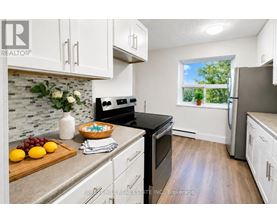 A kitchen with a tile backsplash and a window with a view of trees.