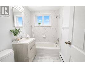 A white bathroom with a marble wall and a window.
