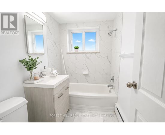 A white bathroom with a marble wall and a window.