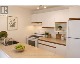 A kitchen with white cabinets and a bowl of green apples on the counter.
