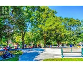 A park with a walking path, trees, and people.