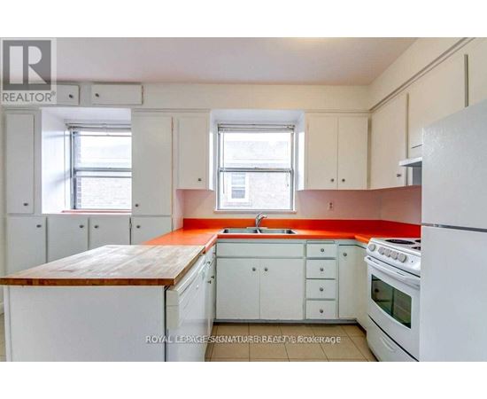 A kitchen with white appliances and cabinets with a red backsplash.