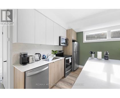 A kitchen with white cabinets and a green wall.