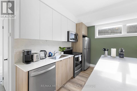 A kitchen with white cabinets and a green wall.