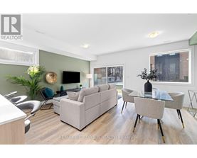 A modern living room with a grey sofa, a glass table, and a TV mounted on the wall.
