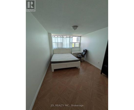 A bedroom with a bed, a chair, and a window.