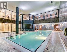 A large indoor swimming pool with a tiled floor and a glass wall.