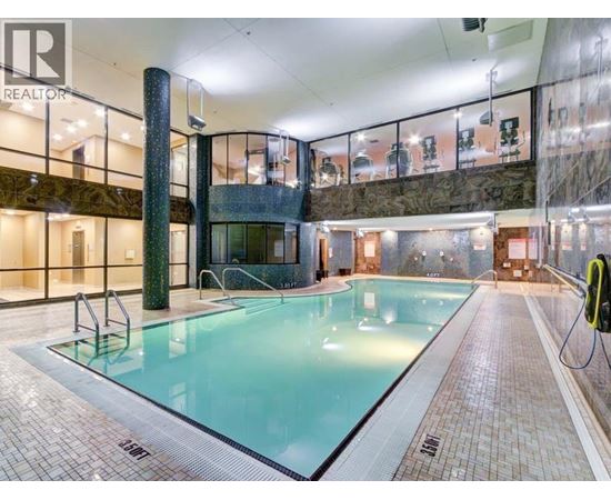 A large indoor swimming pool with a tiled floor and a glass wall.