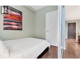 A bedroom with a white bed and a painting on the wall.