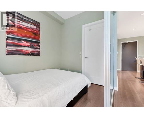 A bedroom with a white bed and a painting on the wall.