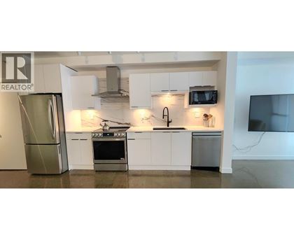 A modern kitchen with white cabinets and stainless steel appliances.