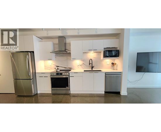 A modern kitchen with white cabinets and stainless steel appliances.