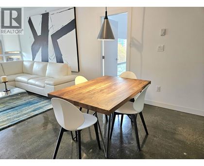 A modern dining room with a wooden table and white chairs.