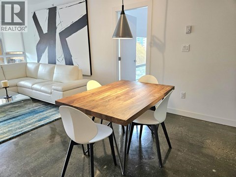 A modern dining room with a wooden table and white chairs.