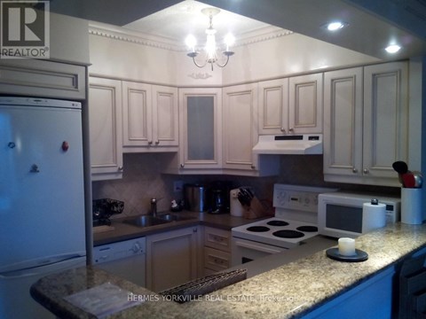 A kitchen with a refrigerator on the left and a microwave on the counter.