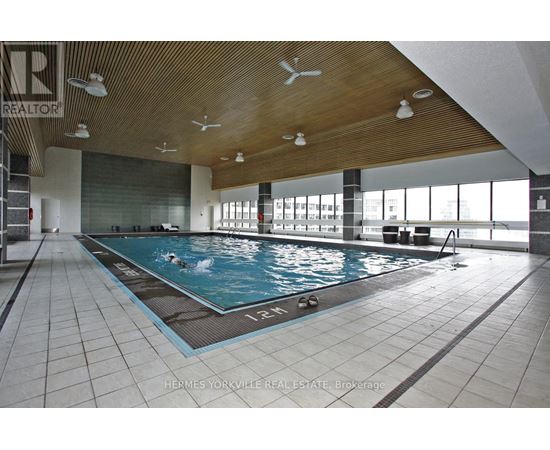 A large indoor swimming pool with a wooden ceiling and tiled floor.