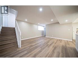 A spacious room with wooden flooring and a staircase leading to another level.