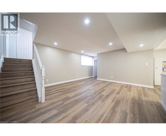 A spacious room with wooden flooring and a staircase leading to another level.