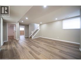A spacious room with wooden flooring and a staircase.