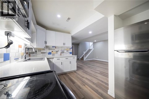 A modern kitchen with white cabinets and a wooden floor.