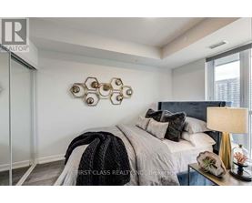 A bedroom with a bed, pillows, a blanket, a lamp, and a decorative wall piece.