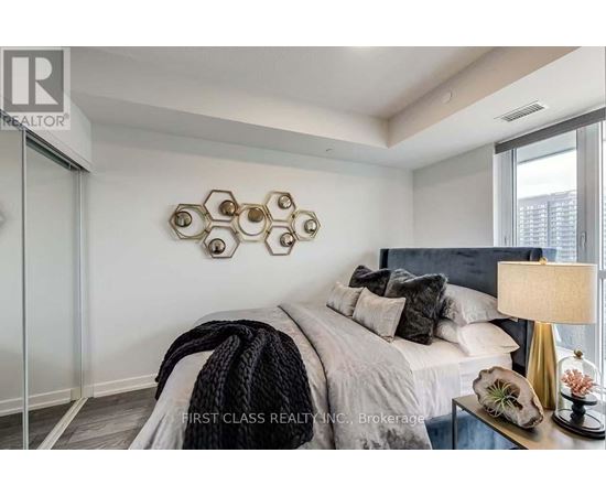 A bedroom with a bed, pillows, a blanket, a lamp, and a decorative wall piece.