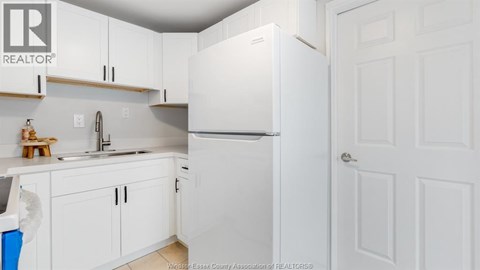A kitchen with white cabinets and a white refrigerator.
