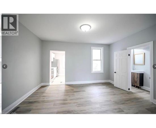 A spacious room with wooden flooring and white walls.