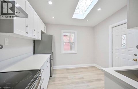 A kitchen with white cabinets and a skylight.