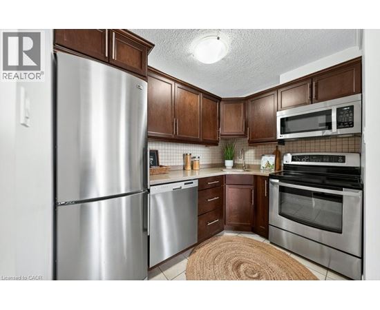 A kitchen with a refrigerator, microwave, oven and stove.