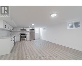 A spacious kitchen with white cabinets and a stainless steel refrigerator.