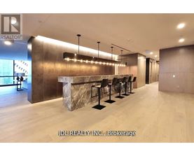 A modern bar area with a row of black stools and a marble counter.