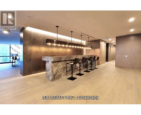 A modern bar area with a row of black stools and a marble counter.