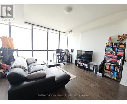 A living room with a black leather sofa and a television.