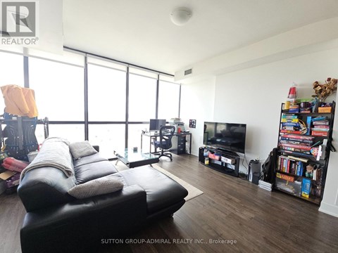 A living room with a black leather sofa and a television.