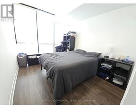 A bedroom with a bed, nightstand, and a window with blinds.
