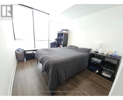A bedroom with a bed, nightstand, and a window with blinds.