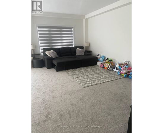 A living room with a black couch and a rug.